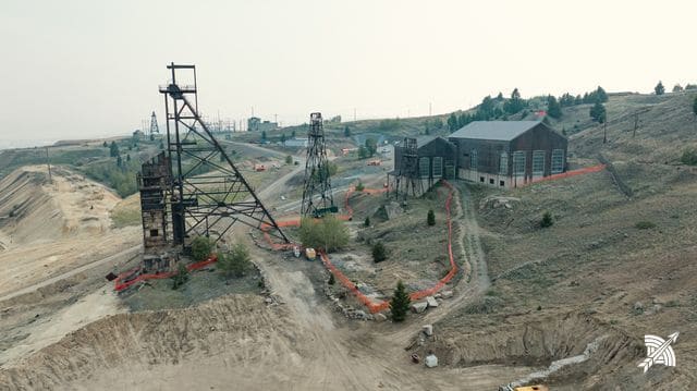 Aerial view of the headframe and hoist house, safety fencing around the ground