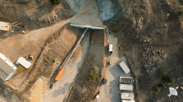 Steep aerial view down onto the portal, ventilation duct and vehicles at the cut