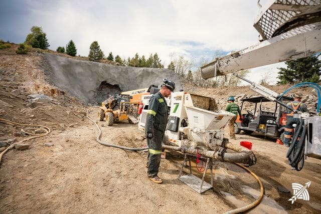 A worker at the concrete pump, hoses run out across the ground