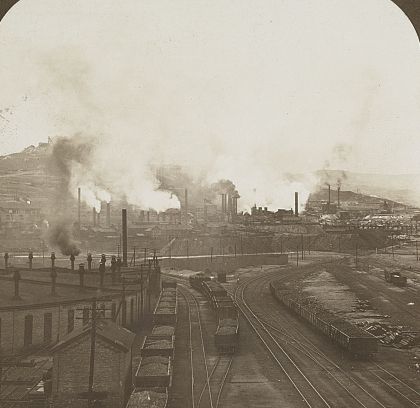 Smelters smoking at the base of Anaconda Hill, ore trains in the foreground, c. 1905